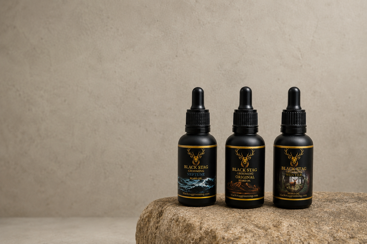 Black Stag Grooming Neptune, Original, and Hunter beard oils in matte black dropper bottles displayed on a stone surface